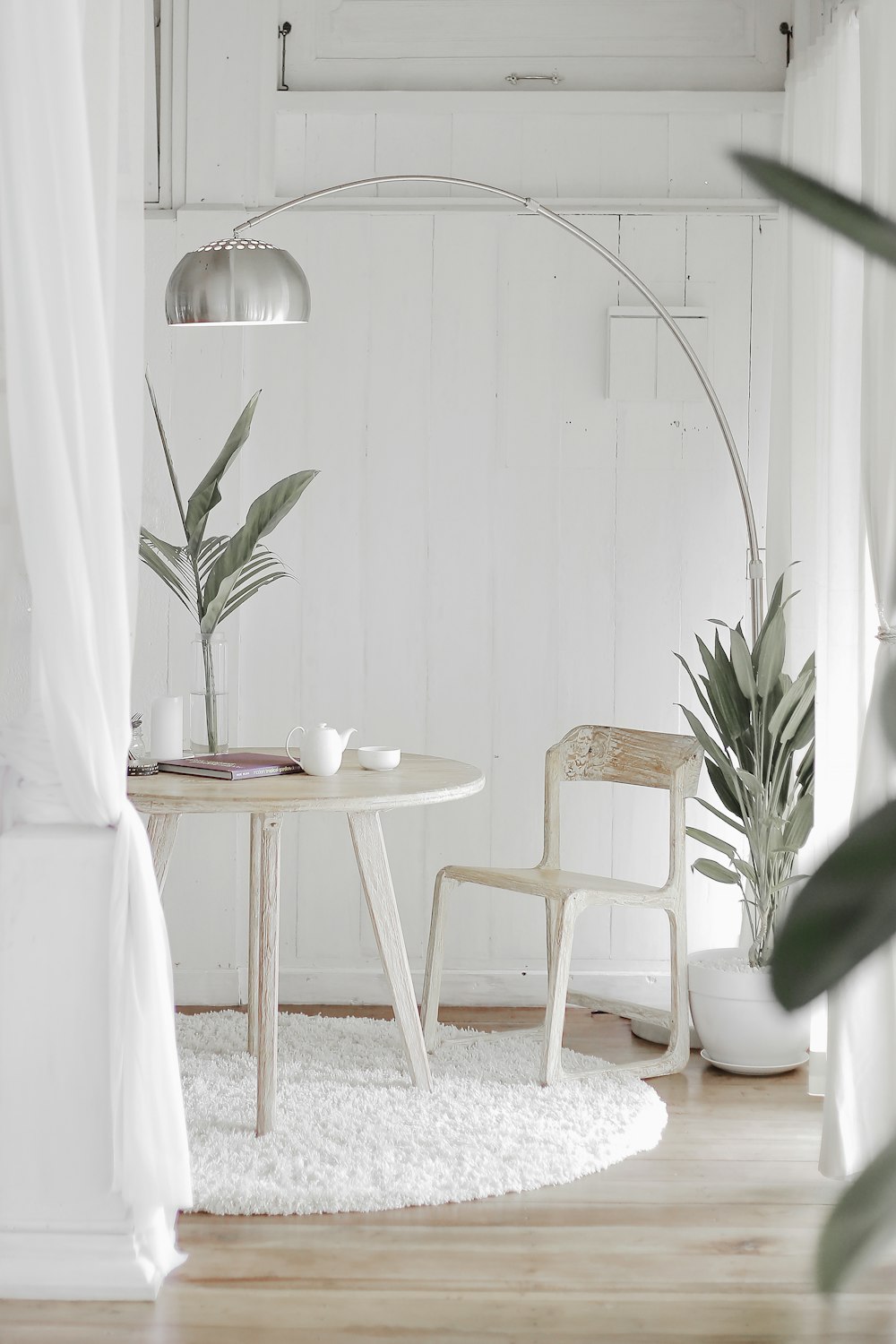 白い敷物の前の丸いテーブルに白いスチール製の椅子