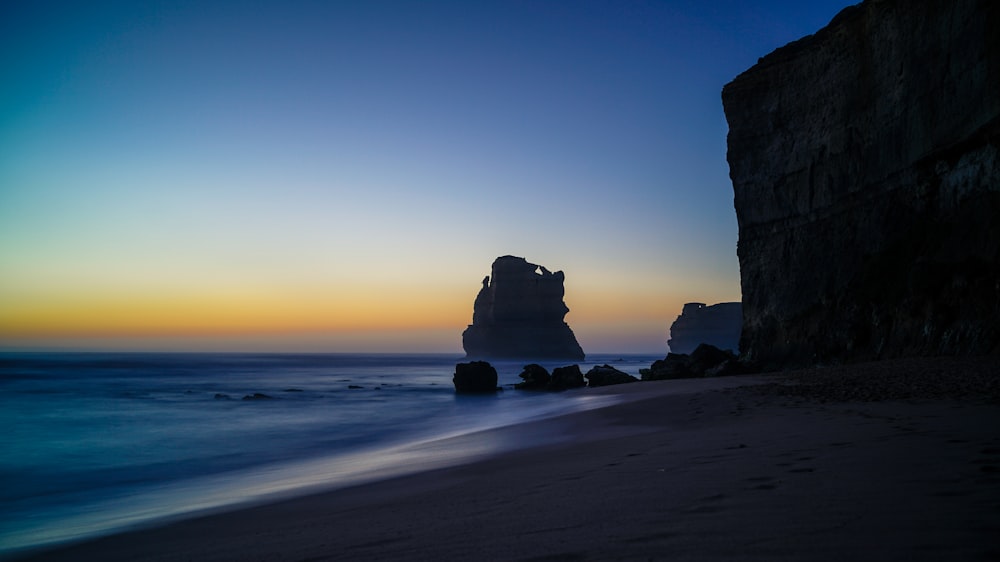 rock formation on body of water during daytime