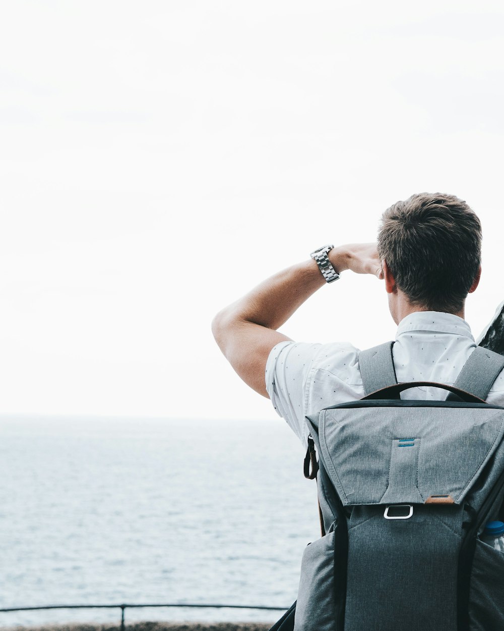 Ein Mann mit einem Rucksack, der auf das Meer blickt