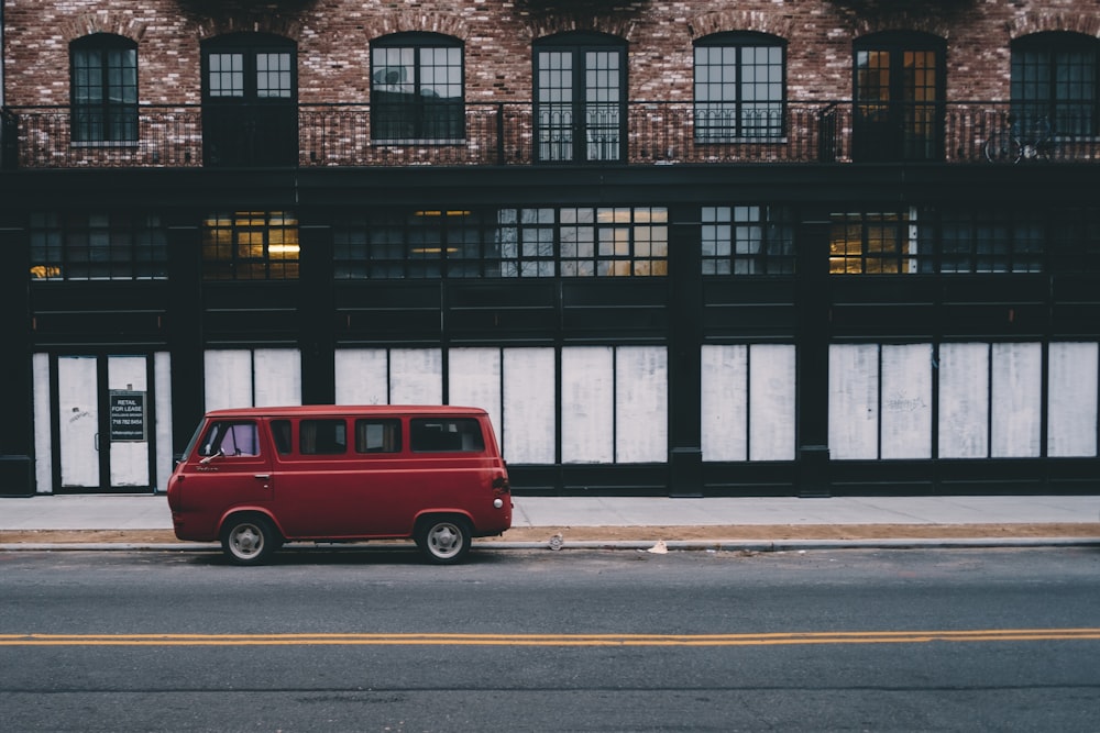 red van on road beside brown concrete house