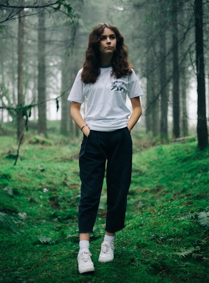 woman standing in middle of forest