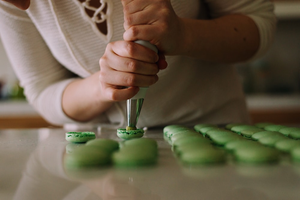 Fotografia de foco seletivo de mulher colocando cereja em cupcakes