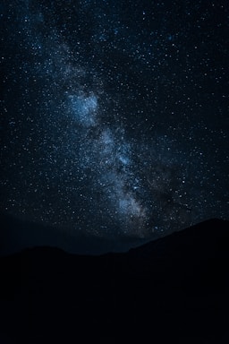 silhouette of mountain under starry night sky