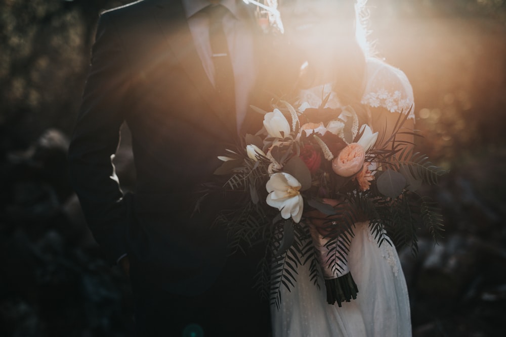 novio al lado de la novia sosteniendo ramo de flores