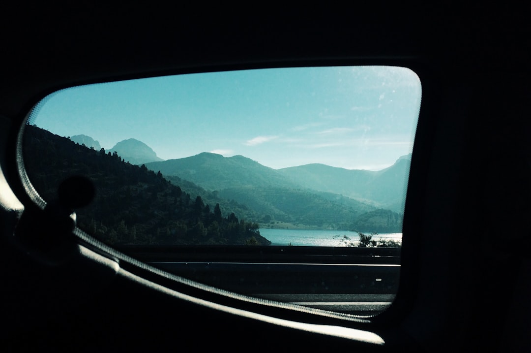 a view from inside a car of mountains and a lake,