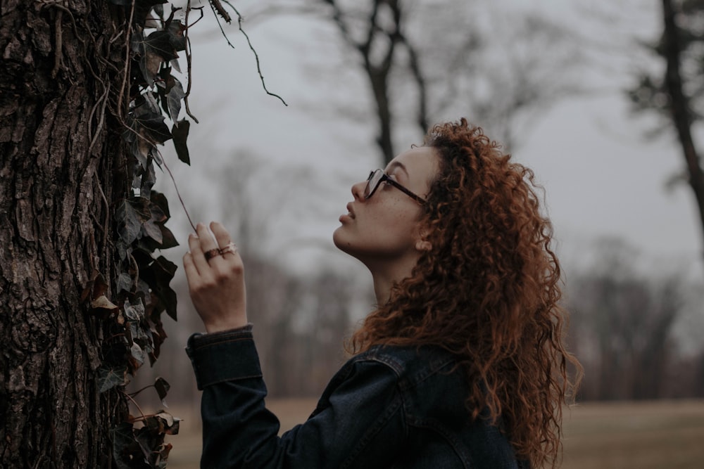 woman holding brown vine of plant near tree