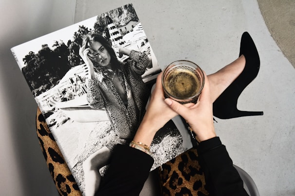 Hands holding a coffee over a fashion magazine representing calm luxury taste, tone and direction.