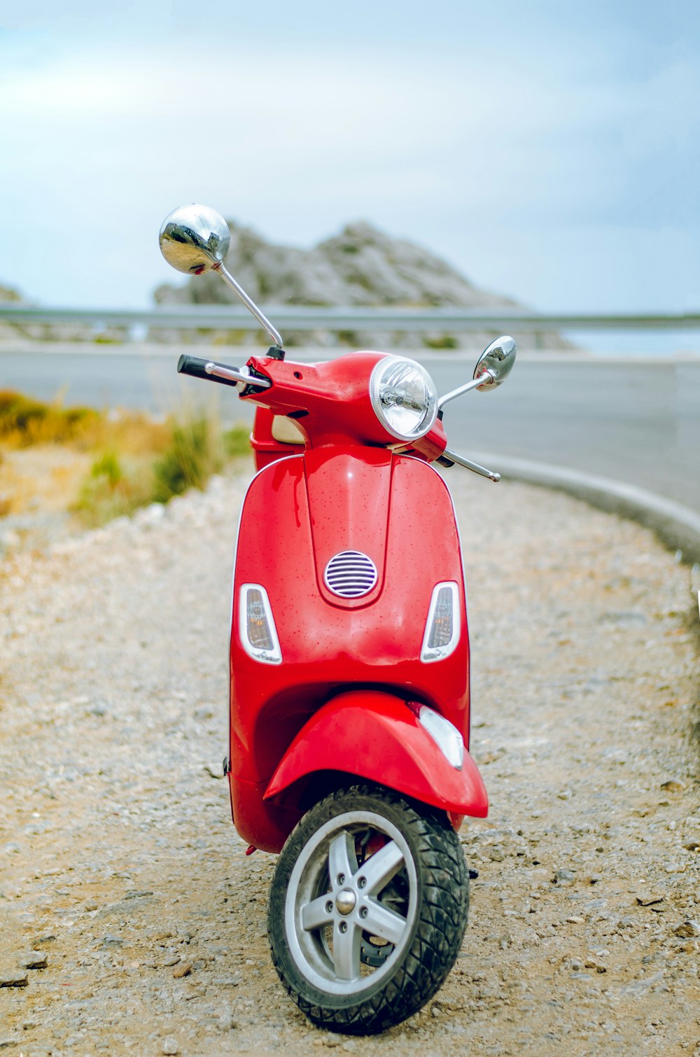 red Vespa motor scooter on side of the road