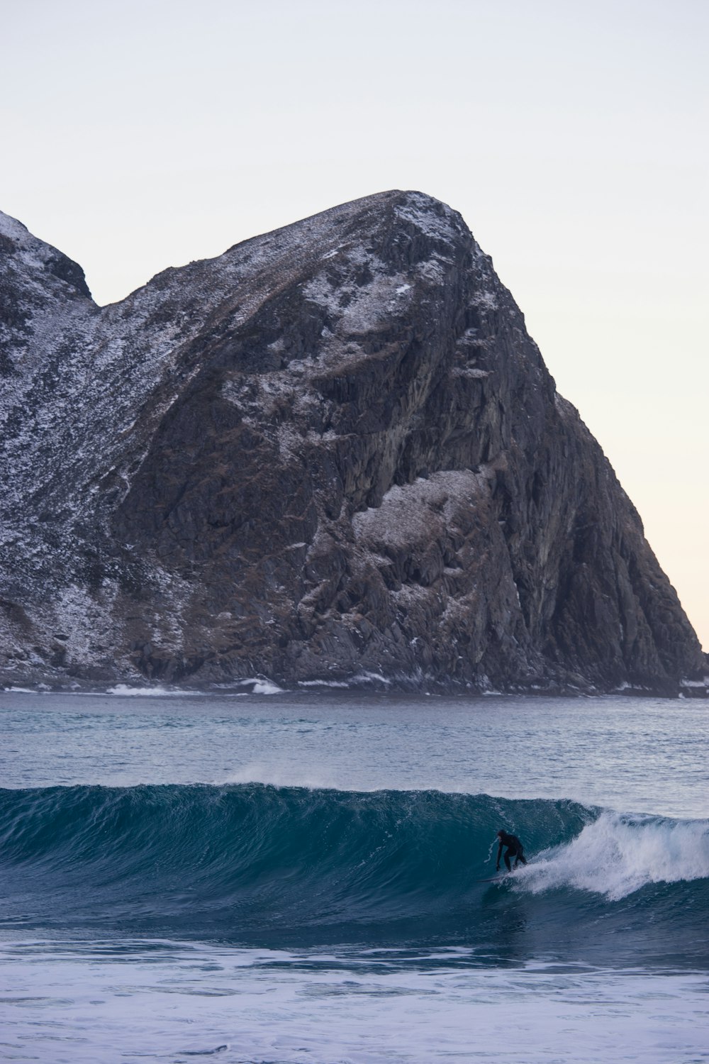 person surfing on sea near mountain