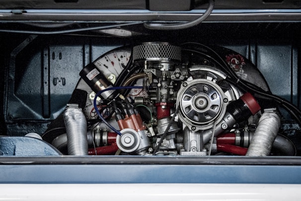 A detailed view of a complex mechanical engine, featuring various metallic components, tubes, and wires. The engine is housed within a vehicle compartment, showcasing its intricate design and craftsmanship.