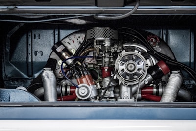 A detailed view of a complex mechanical engine, featuring various metallic components, tubes, and wires. The engine is housed within a vehicle compartment, showcasing its intricate design and craftsmanship.