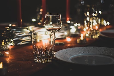 selective focus photography of wine glass and shot glass on table dine zoom background