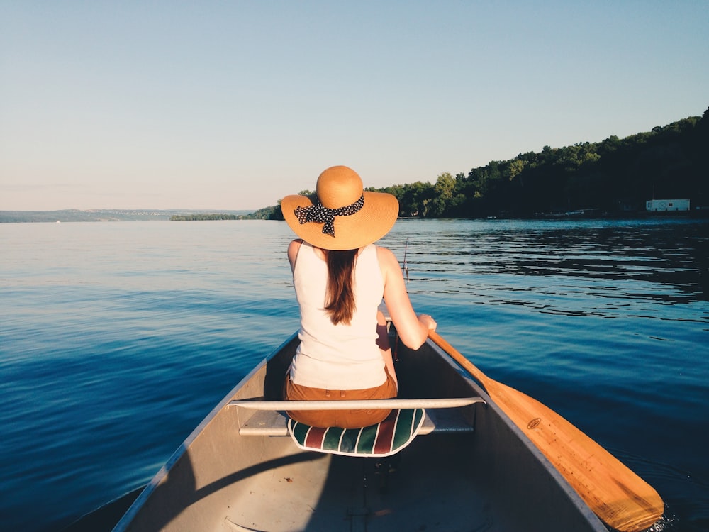 Mujer con sombrero de sol montando bote en el cuerpo de agua