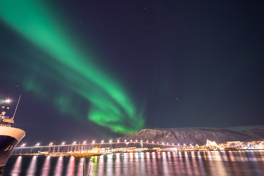 a boat in the water with an aurora light in the sky