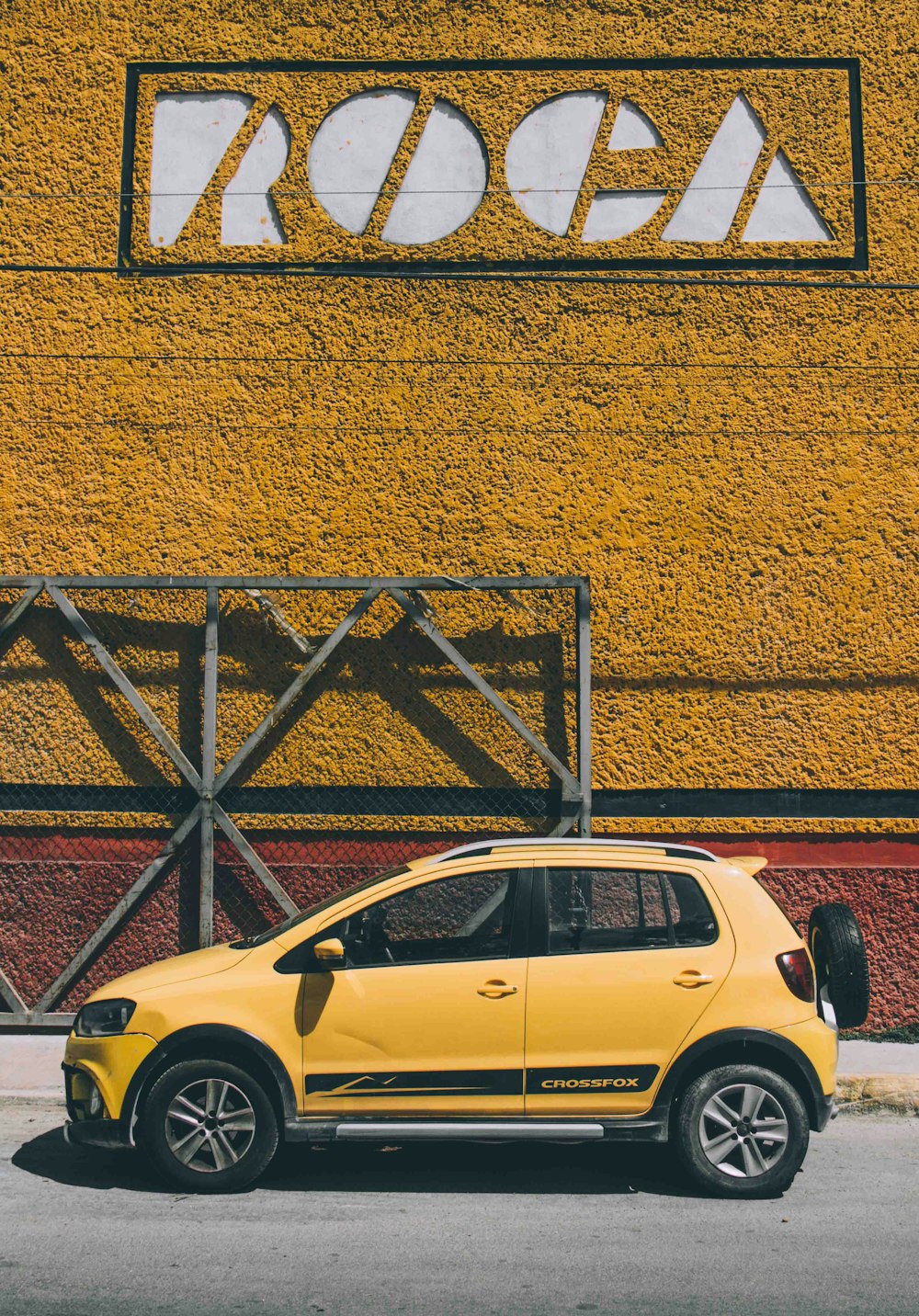 yellow 5-door hatchback parked beside brown metal frame