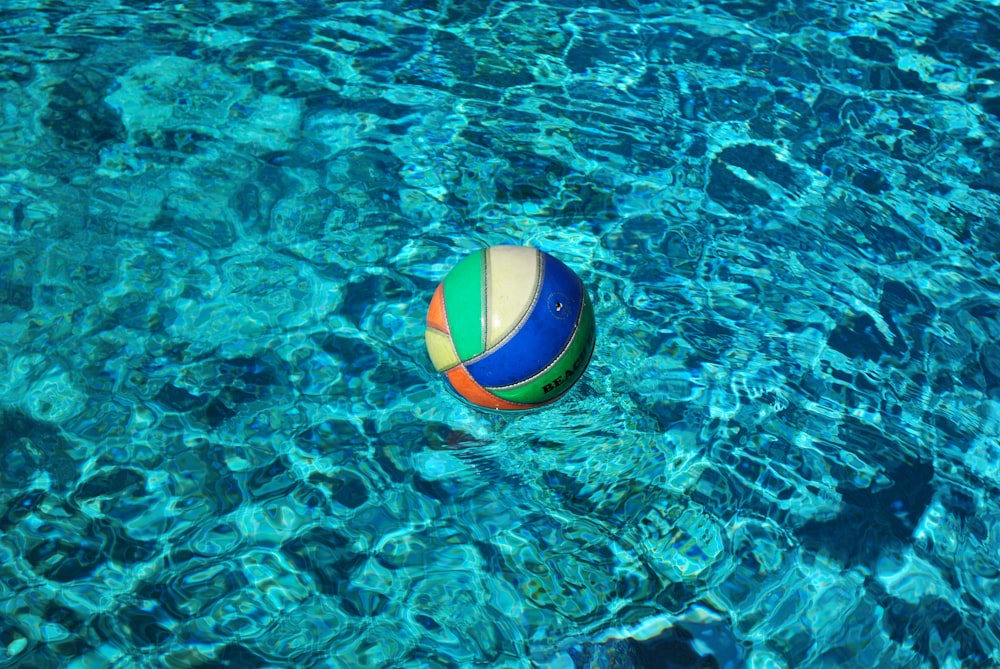 blue and multicolored volley ball on body of water