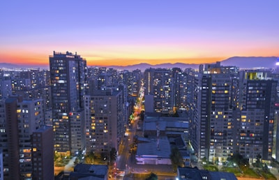 High-rise cityscape at sunset with illuminated buildings.
