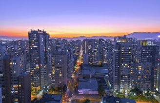 High-rise cityscape at sunset with illuminated buildings.