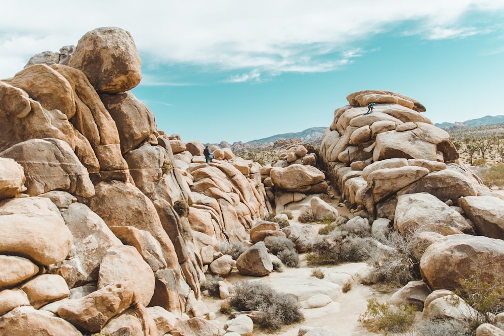 people standing on rock formation under cloudy sky