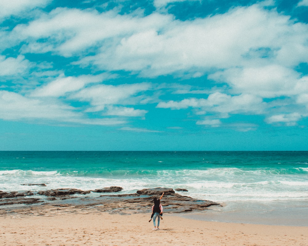 person carrying another person on the back on the beach