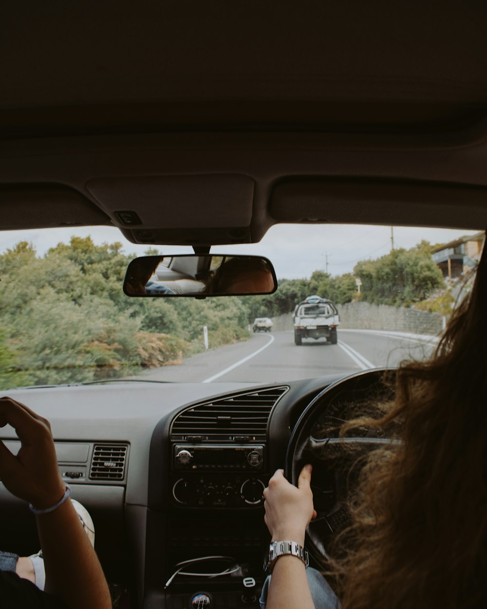 Mujer conduciendo coche en carretera arbolada durante el día