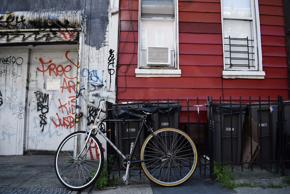 black bicycle leaning on black steel fence