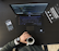A workspace setting featuring an open laptop displaying code, a smartphone with a camera app open, a person's hand holding a cup of coffee, and a book titled 'Trend-Driven Innovation'. The person is wearing a watch and bracelets.
