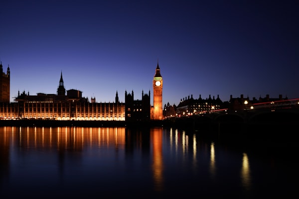 Photo of UK Parliament at night. Lights reflecting on the Thames.