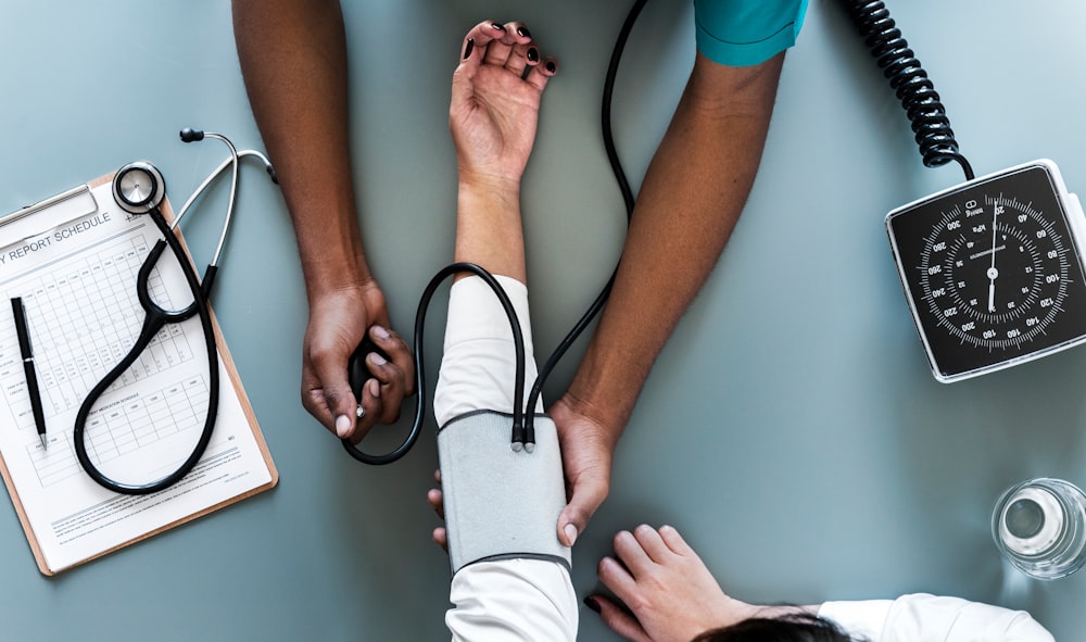 aerial view photography of person holding arm while pressing blood pressure machine