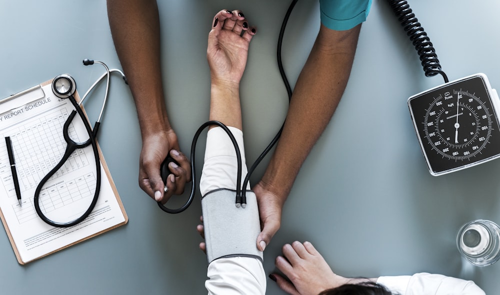 aerial view photography of person holding arm while pressing blood pressure machine