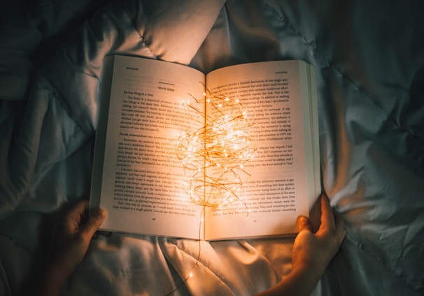 person holding string lights on opened book