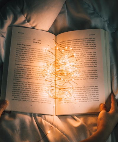 person holding string lights on opened book