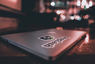 Close-up of a vibrant UFO vinyl sticker on a laptop corner, glowing under soft light.