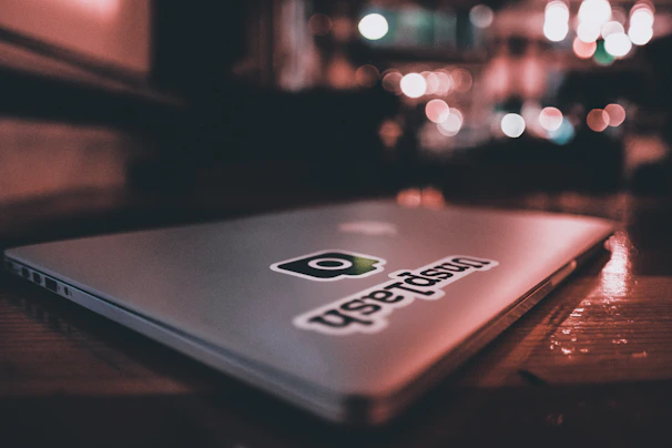 Close-up of a vibrant UFO vinyl sticker on a laptop corner, glowing under soft light.