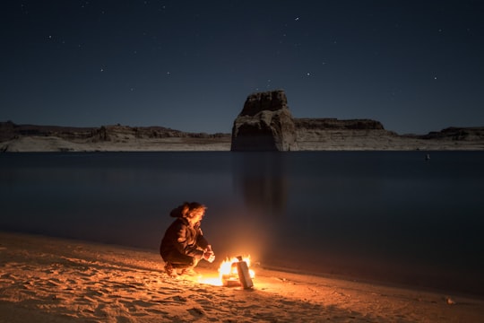 person sitting beside bonfire on seashore in Lake Powell United States