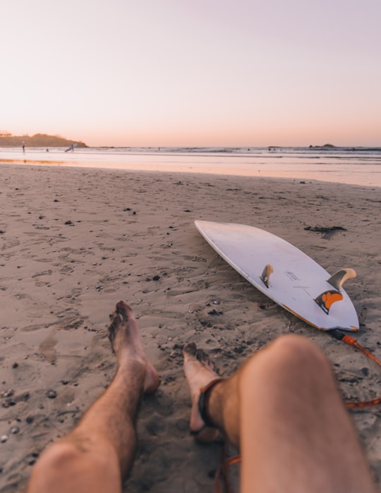 person sitting on seashore near surfboard in front sea in Tamarindo Costa Rica