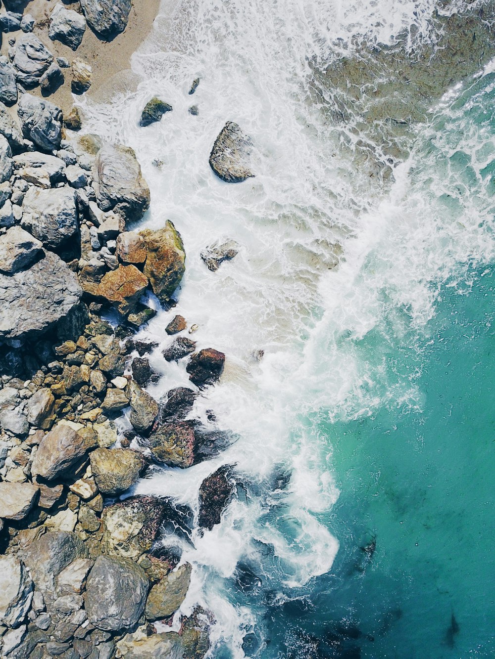 aerial view photography of sea waves near rocks