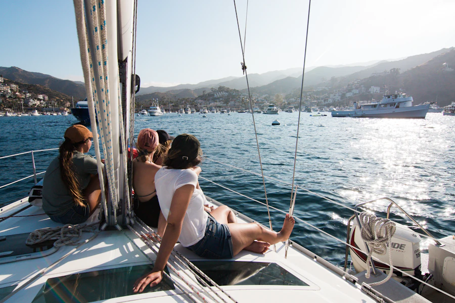 Guests sitting on the deck of a sailing boat as it crosses a sunny bay