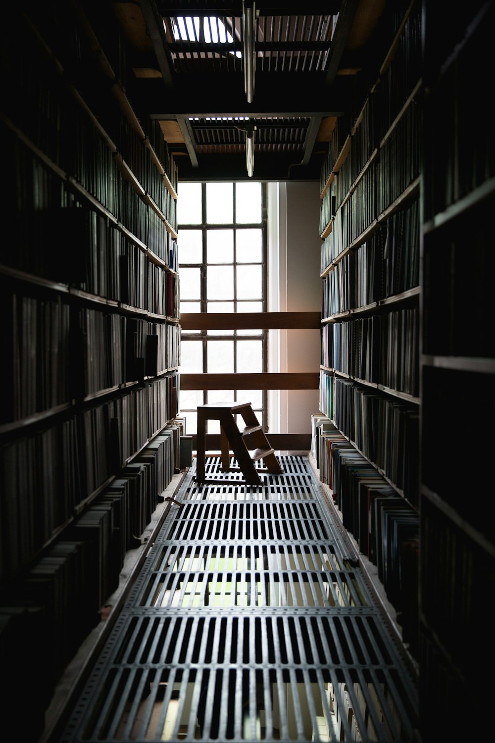 Mini escalera de madera marrón en medio de las estanterías de libros