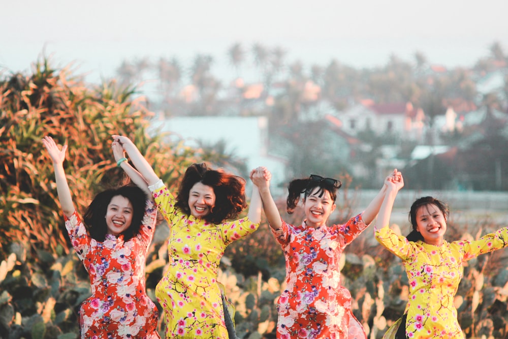 four women holding hands while jumping