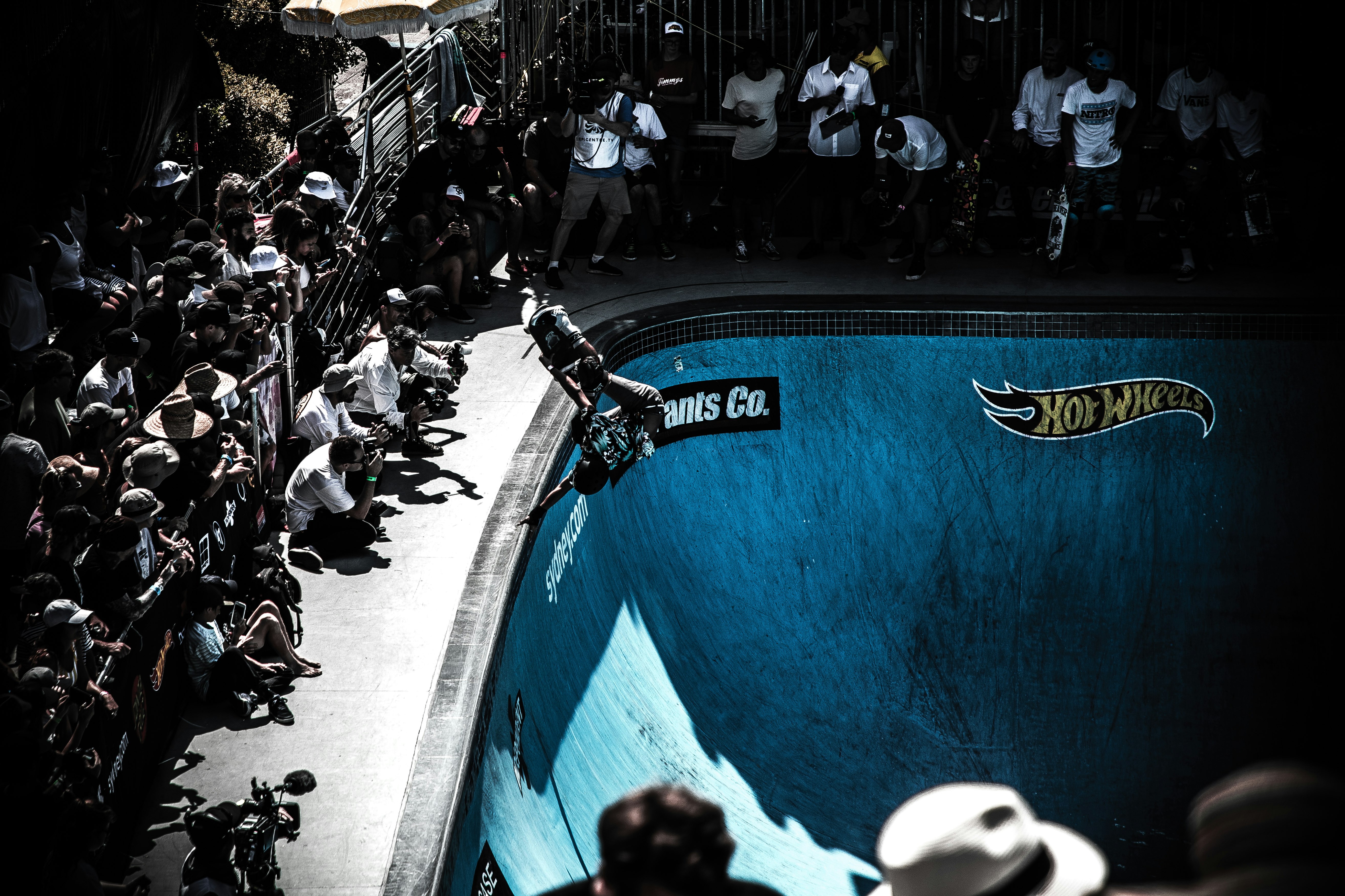 people looking at man performing skateboard on skateboard bowl