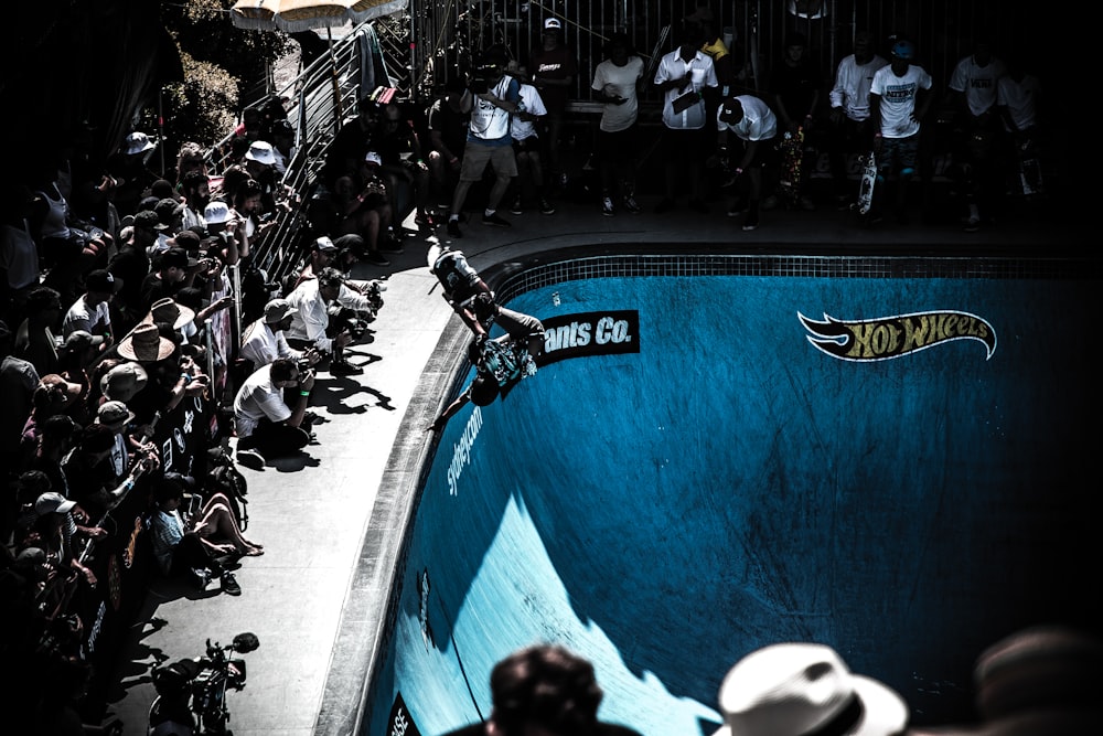 people looking at man performing skateboard on skateboard bowl