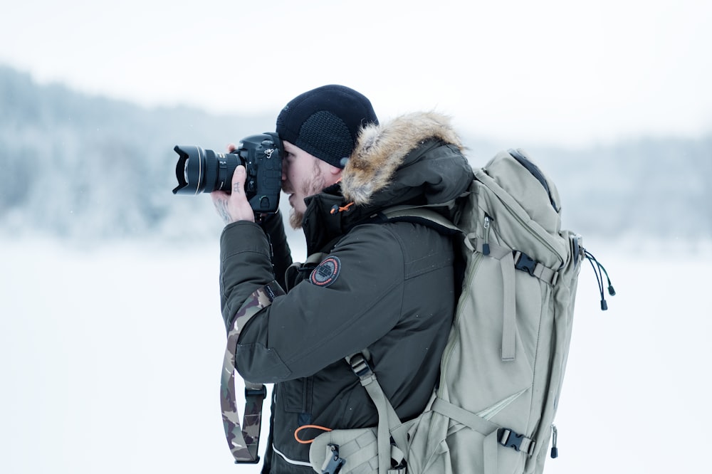 man standing on snow field while taking photo