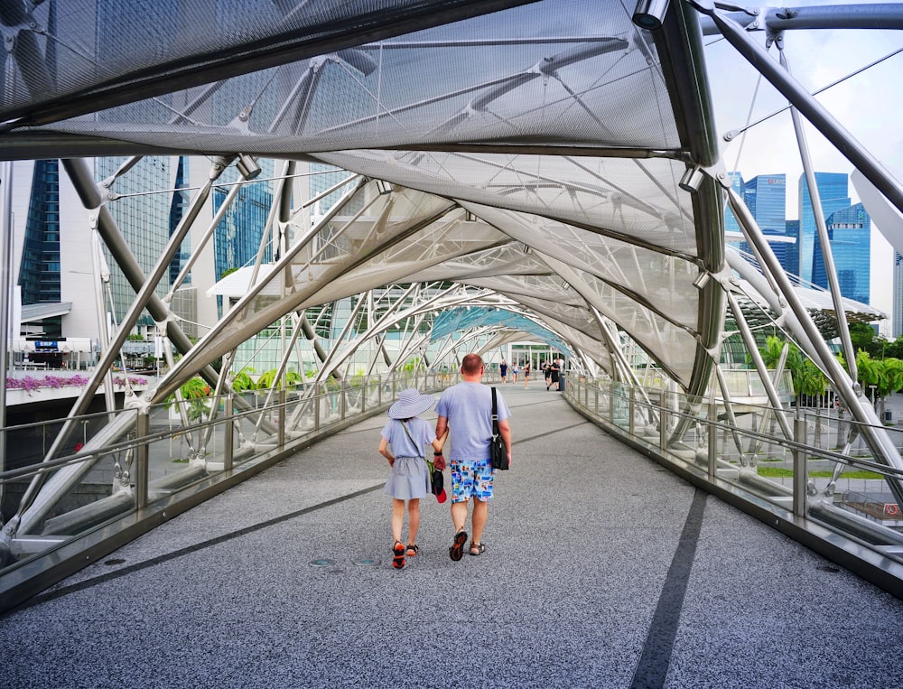 man and woman walking inside clear glass roof pathway at daytime