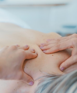 person massaging the back of a woman