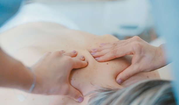 person massaging the back of a woman