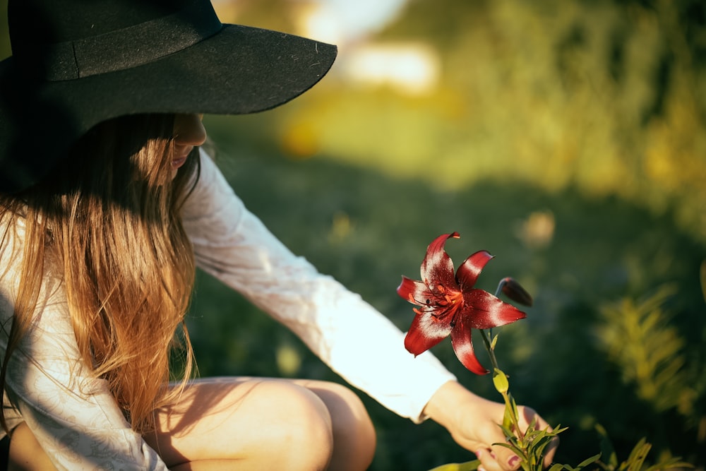 woman picking red flower during daytime