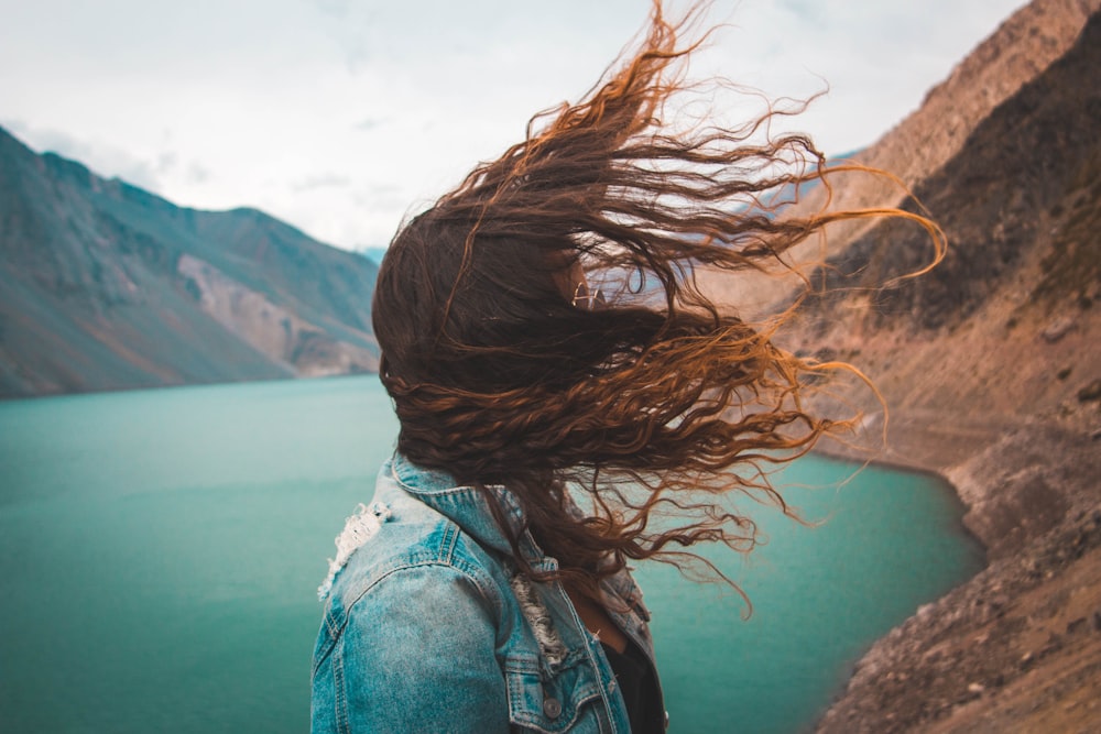 woman's hair covering her face near body of water