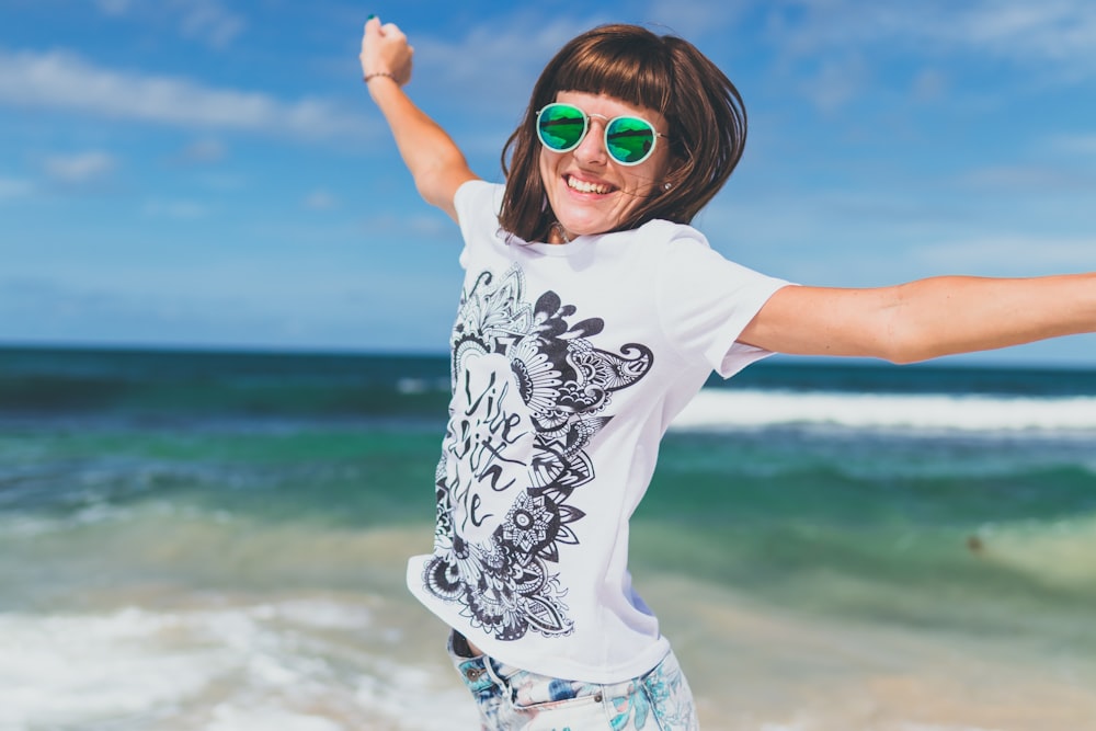 femme portant une chemise blanche et noire sautant près du bord de mer