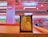 A pin art toy with yellow pins is placed on a wooden surface in a brightly colored room. The background is a blur of pink and teal hues, suggesting a retail setting like a store with shelves visible.